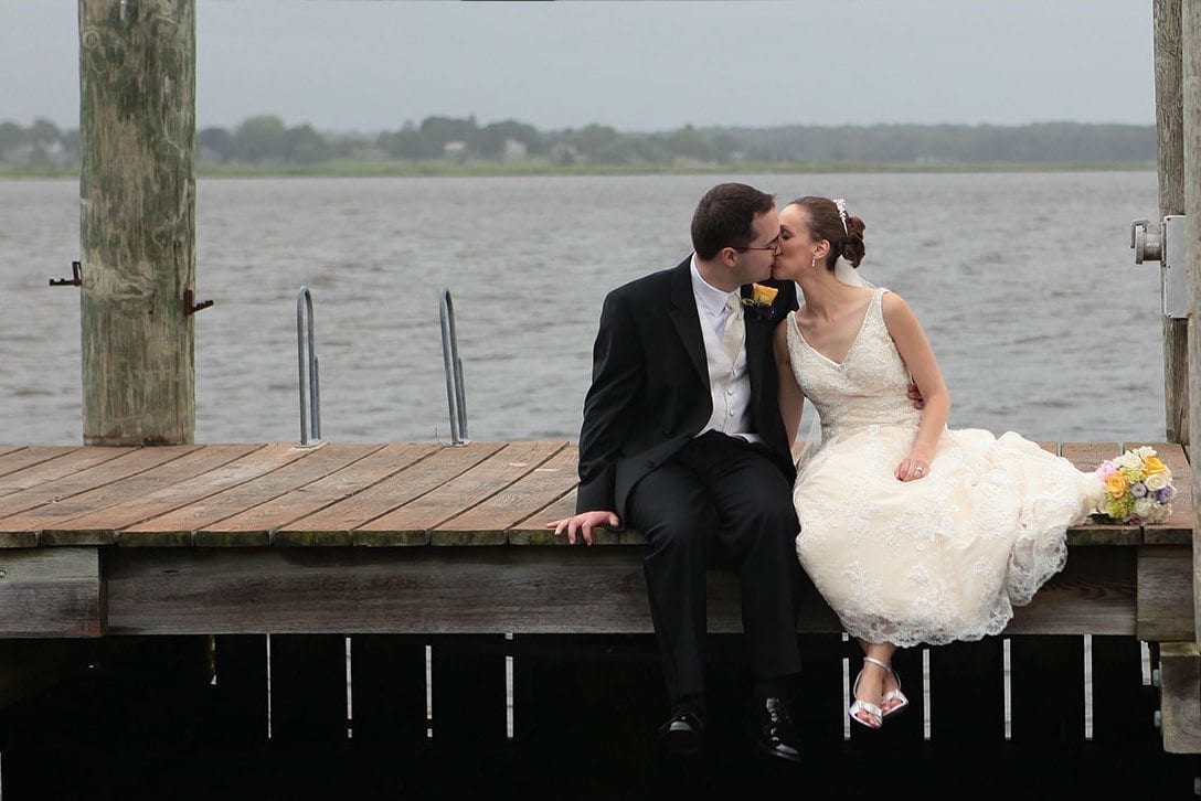 Bride and groom kissing on dock.