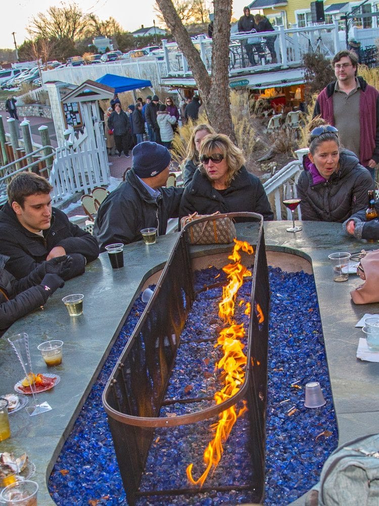 Chilly Patrons At The Marina Bar Around A Fireplace With Cocktails