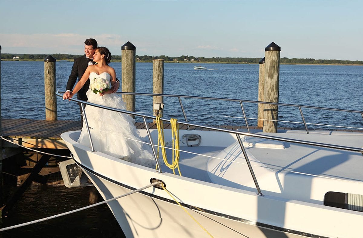 Bride and groom standing on bow of boat.